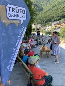 Kinder auf der Bank, Dame liest ein Buch vor